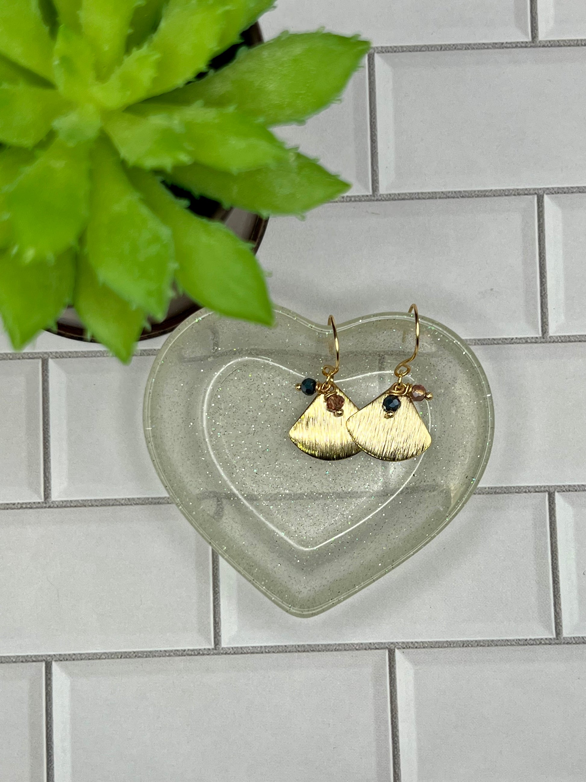 a pair of earrings sitting on top of a heart shaped plate