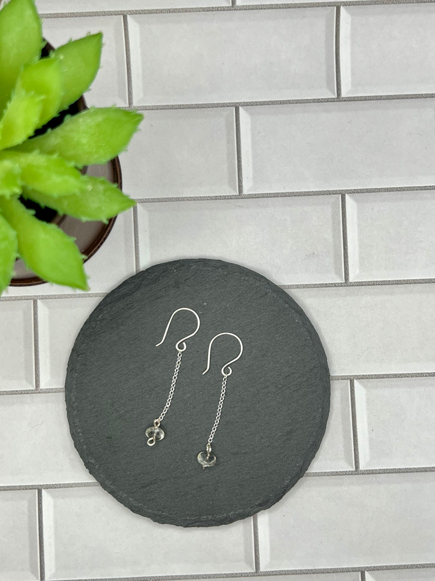 a pair of earrings sitting on top of a black plate